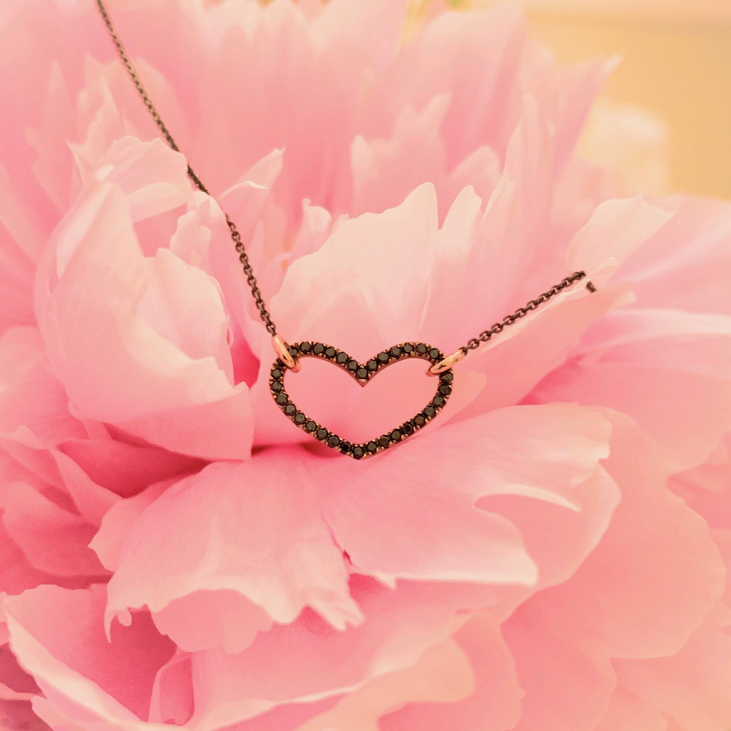 Black diamond floating heart with onyx gold chain laying on pink flower - Boussidan Joaillerie